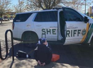 suspect_seated_in_handcuffs_by_MCSO_vehicle.jpg